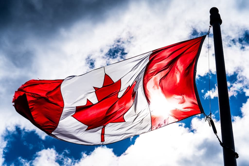 Canadian flag flying on a partly cloudy day.